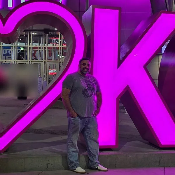 Jeff at the lit-up heart and KC sign outside T-Mobile Center in downtown Kansas City at night.