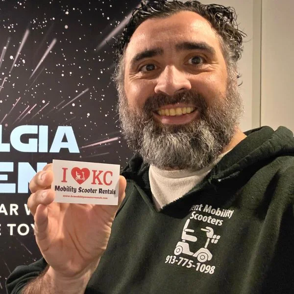 Jeff holding a KC Mobility Scooter Rentals card at a museum exhibit.