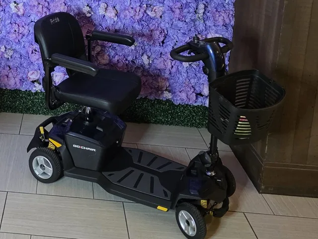 Navy Pride Go-Go LX with CTS 4-wheel mobility scooter parked in front of a purple flower wall in a Kansas City hotel