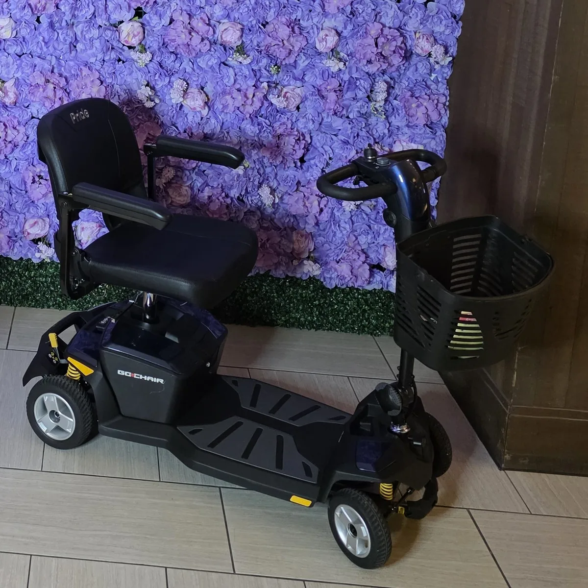 Navy Pride Go-Go LX with CTS 4-wheel mobility scooter parked in front of a purple flower wall in a Kansas City hotel