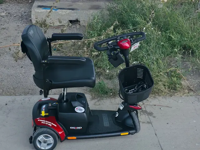 Red Pride Go-Go Traveller 3-wheel mobility scooter in front of a blue lips street-art mural in the West Bottoms, Kansas City
