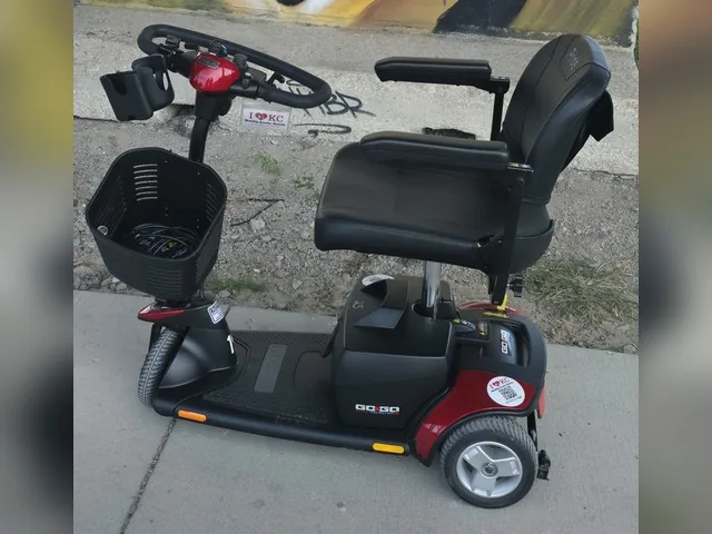 Red Pride Go-Go Elite Traveller 3-wheel mobility scooter on a sidewalk in front of a gold marquee-lights mural in the West Bottoms, Kansas City