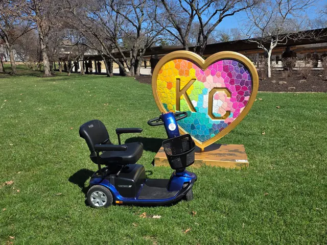 Blue Pride Victory 10 3-wheel mobility scooter beside a rainbow mosaic KC heart sculpture in Kansas City