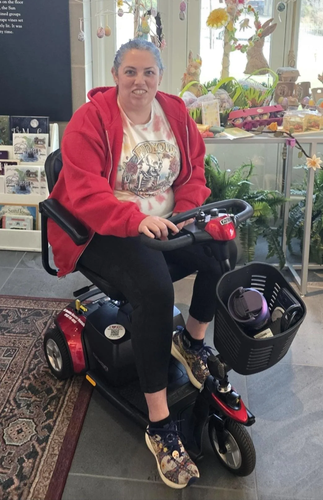 An owner of KC Mobility Scooter Rentals seated on a Pride Go-Go three-wheel scooter during a Kansas City outing