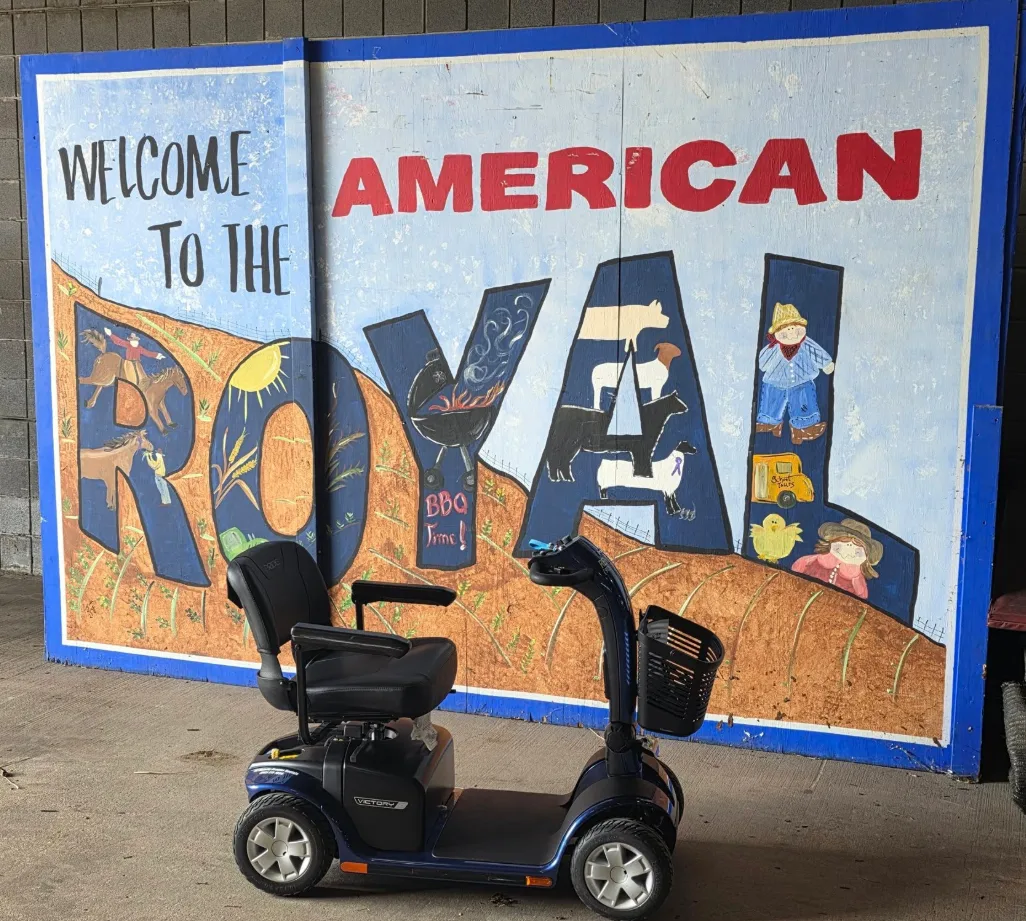 Pride Victory 10 mobility scooter in front of a hand-painted welcome mural for a Kansas City heritage agricultural and BBQ trade fair