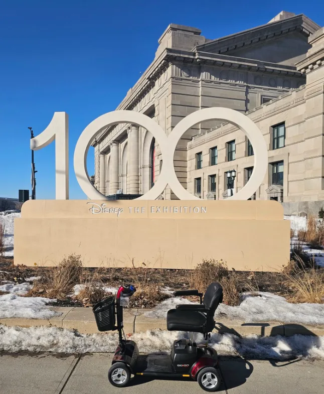 Pride Go-Go mobility scooter parked outside Union Station Kansas City in front of a large white sculptural exhibition installation